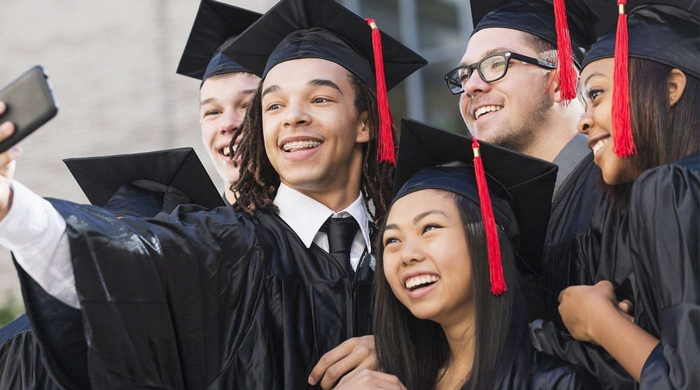 High school students taking a selfie in graduation caps and gowns