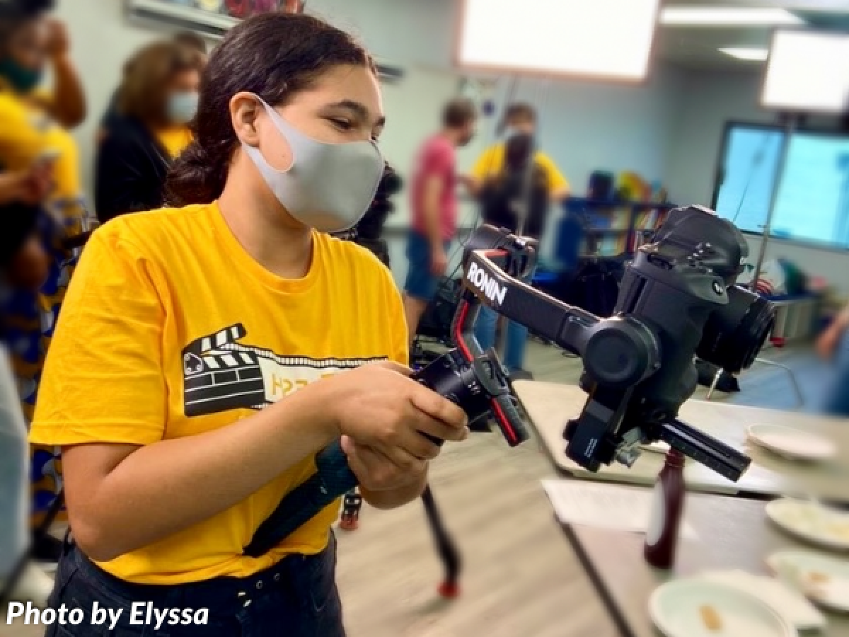 Young girl filming with camera in school 