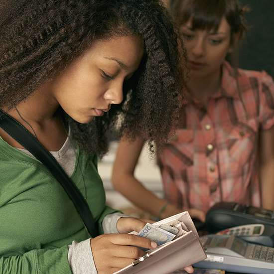 Teen puts cash into their wallet.